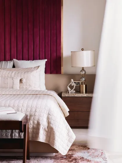 A soft, ethereal view of the master bedroom, highlighting the plush textures of the bedding and the elegant bedside lamp. The design creates a romantic and serene atmosphere.