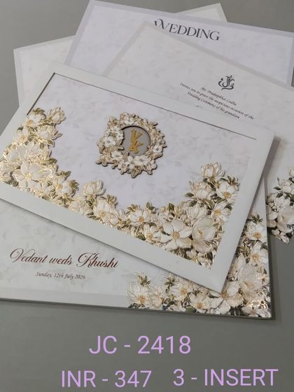 This stunning invitation features a wreath of 3D white and gold flowers with a custom monogram at the center. The design is clean, luxurious, and comes with three inserts.