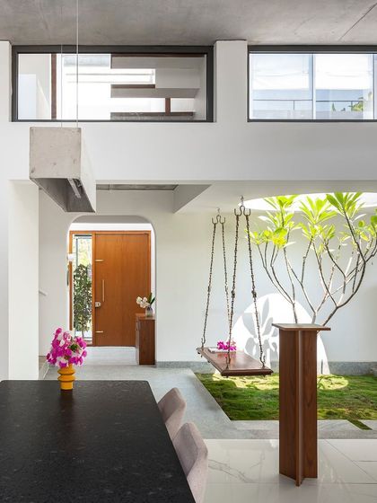 Another perspective of the main living volume, showcasing the interplay between the dining area, the arched entryway, and the green courtyard. The design prioritizes clear sightlines and spatial fluidity.