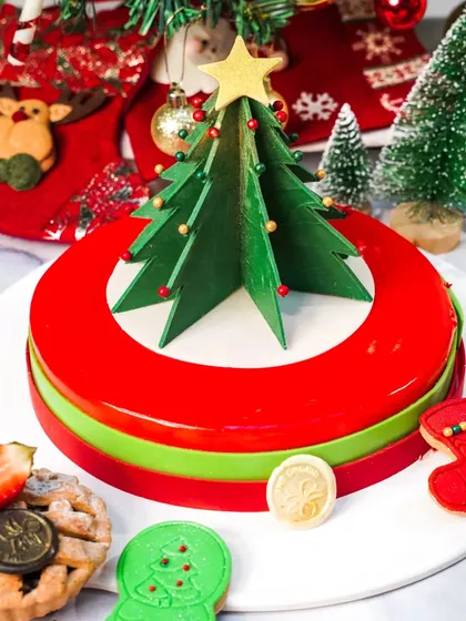 A modern Christmas entremet cake with a glossy red glaze and a graphic chocolate tree. The clean, bright styling makes it a sophisticated and contemporary holiday dessert.