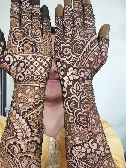 A client happily showing off her full-coverage mehendi. The design is a beautiful mix of leafy vines and floral patterns, creating a very organic and flowing look.