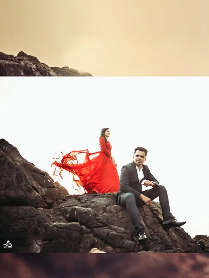 A powerful and elegant shot of a couple on the rocks, with the bride's red dress flowing in the wind.