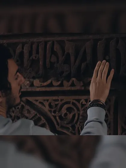 A close-up detail shot from the Red Fort. I noticed this person admiring the intricate calligraphy carved into the stone, a quiet moment of connection with history.