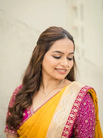 A smiling bride in her yellow saree. The makeup is minimal and fresh, with a simple bindi and nath, letting her natural happiness be the focus.
