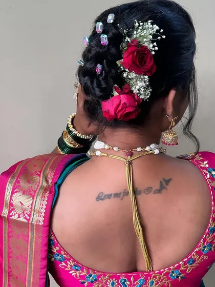 A beautiful view of the bridal hairstyle from the back, showing the intricate bun, fresh roses, and the bride's tattoo. I always work to incorporate the bride's personal style.
