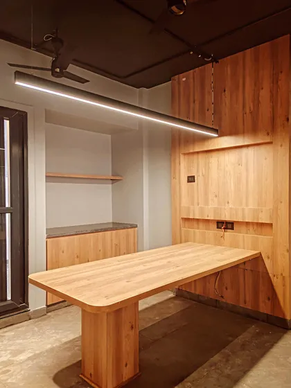 Functionality meets style with this custom-designed wooden table and integrated wall unit. The sleek, linear pendant light illuminates the workspace, demonstrating our focus on creating practical yet aesthetically pleasing furniture solutions for modern offices.