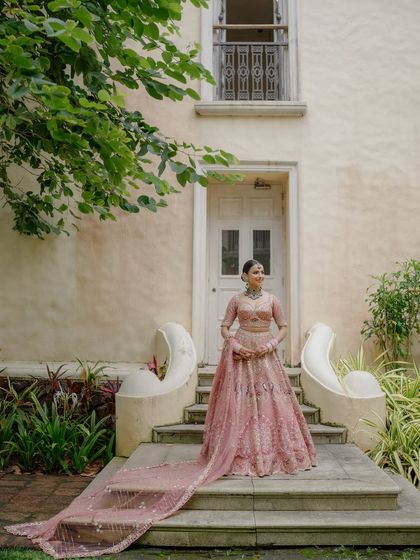 A full-length view of this bride's stunning pastel lehenga with a long, elegant train. Her makeup and hair are styled to match the grandeur of the outfit.