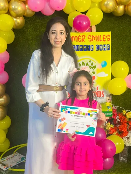 A proud moment for this little one at our summer camp finale. Her bright dress matches her bright smile. We love celebrating our campers' achievements.