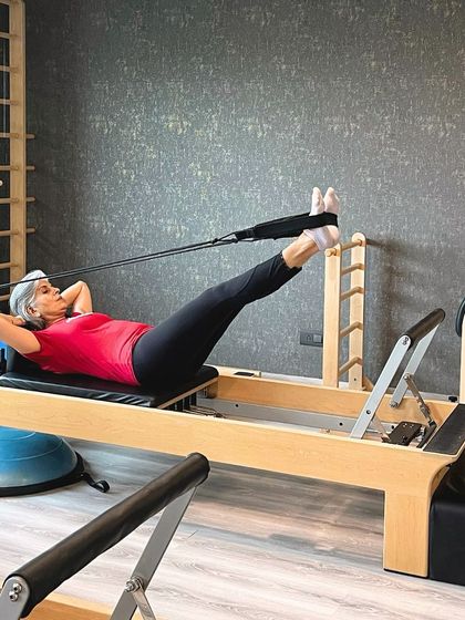 This inspiring client proves that age is just a number. She is working on core strength and flexibility on the reformer, demonstrating the lifelong benefits of a consistent Pilates practice.