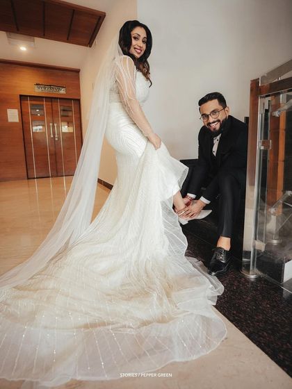 A playful and charming moment as the groom helps the bride with her shoe, showcasing their fun and loving relationship.