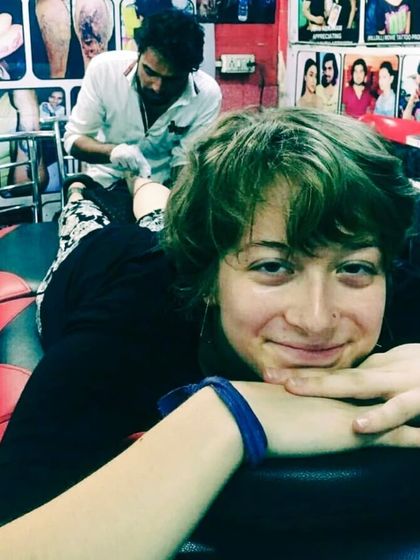 A client from another country relaxing while getting a tattoo on her leg.