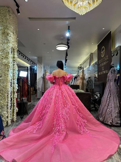 Another angle of the pink ball gown's train in the studio. The corset back and off-shoulder ruffled sleeves are visible, showcasing the craftsmanship.