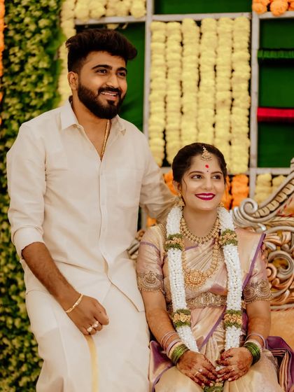 A candid moment captured during a baby shower celebration. The couple is dressed in beautiful traditional clothing, surrounded by festive decorations of marigold flowers, reflecting the joyous and cultural atmosphere of the event.