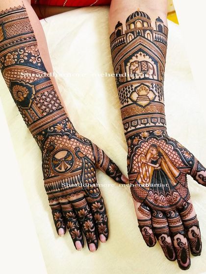 A truly royal bridal design. One palm features a portrait of the bride in a veil, while the arms are adorned with palace architecture, elephants, and a spinning wheel (charkha) motif.