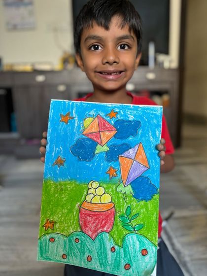 A young boy shows his drawing of kites flying in the night sky, a creative take on the Makar Sankranti theme. My classes are all about encouraging unique ideas.