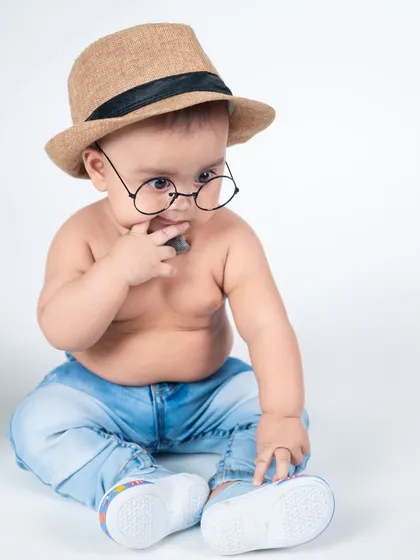 A thoughtful little man in his hat and glasses. This simple studio portrait on a white background is clean, classic, and full of personality.