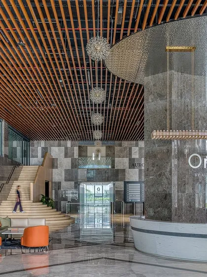The grand, double-height lobby of the Aurobindo Orbit commercial building in Hyderabad. We used a rich palette of marble and wood, with a custom-designed metal jali screen, to create a sense of arrival that blends commercial sophistication with regional context. The space is designed to feel both impressive and welcoming, setting a new standard for corporate interiors.