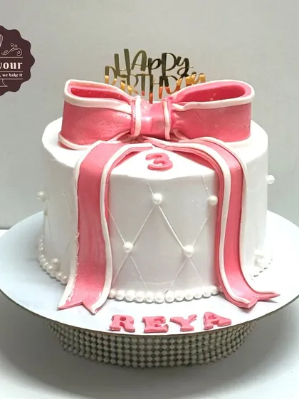 A white and pink bow theme cake for a 3rd birthday. The quilted pattern on the side adds a touch of classic elegance.