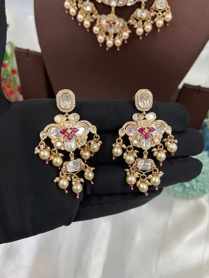 The matching earrings for the 'Noor Nazaakat' set, held to show their design.