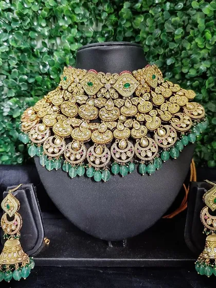 Make a bold statement with this breathtaking all-green bridal set. This rental piece features layers of intricate kundan work, beautifully complemented by cascading green beads and matching jhumka earrings. It is a perfect choice for brides who want to add a vibrant pop of color to their wedding ensemble.