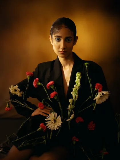 A wider shot from the floral portrait series, showing how the flowers are integrated into the blazer. The pose is strong and fashion-forward.