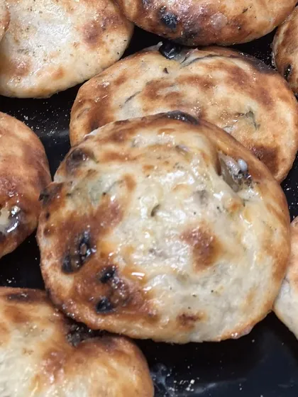 A close-up of the freshly baked Truffle Oil Cheese Kulchas. The golden-brown crust and soft, cheesy interior make them the perfect accompaniment to the spicy chole.