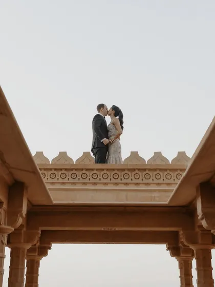 A kiss atop the ramparts of Suryagarh, Jaisalmer. The symmetrical architecture frames this epic, romantic moment against the sky, creating a powerful and memorable pre-wedding photograph.