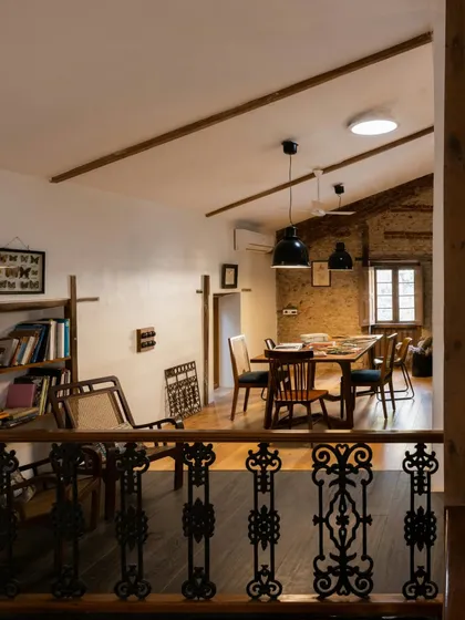 Looking down from the mezzanine, you can see the layers of the studio. The restored iron railing, the exposed brick, and the warm wooden floors all come together. This perspective shows how we created different levels and functions within the original structure.