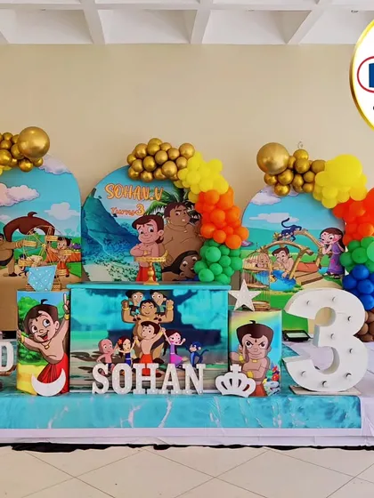 A vibrant Chhota Bheem-themed third birthday party. This setup features multiple backdrops with scenes from the show, character cutouts, and colorful balloon columns.