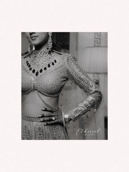 A black and white detail shot of the bride's stunning blouse and jewelry. This close-up focuses on the intricate craftsmanship and modern design of her bridal attire, creating a high-fashion portrait.