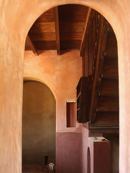 A passageway in the Doddaballapura mud house, where different natural finishes meet. The textures of lime-oxide plaster, cow dung plaster, and rustic wood create a visual and tactile journey through the home.