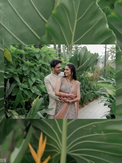 A creatively framed shot of the couple, seen through large tropical leaves. This composition adds an artistic and intimate feel to their romantic portrait.