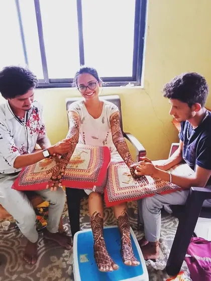 Here you can see my team and me at work during a home service appointment. We are applying intricate bridal mehandi on both the hands and feet of our client.
