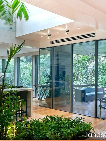 We blur the boundaries between indoor and outdoor living by bringing nature inside. In this private residence, an indoor planter with tropical foliage sits under a large skylight, creating a vibrant, light-filled space that feels like a private conservatory.