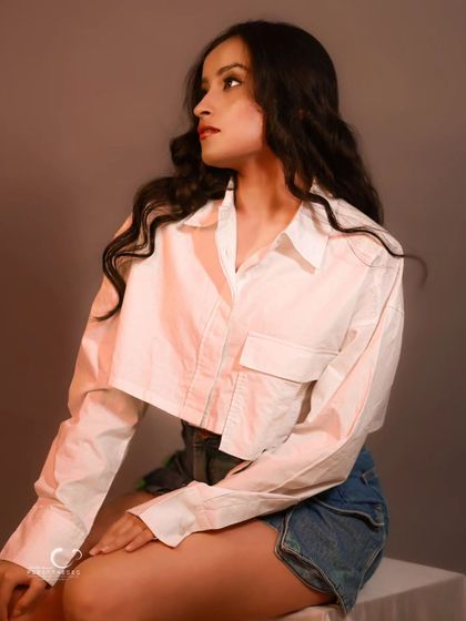 A casual and modern studio look. The simple white shirt and denim skirt are timeless, and the lighting creates a soft, flattering glow.
