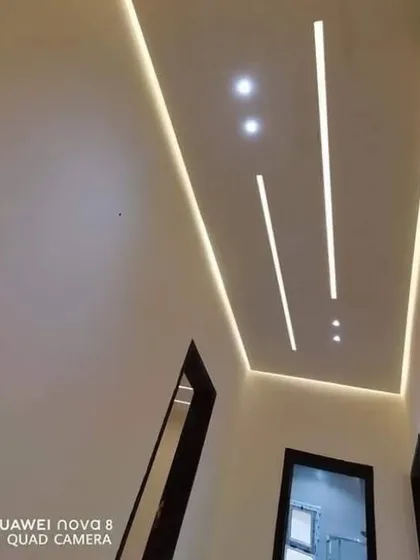 A minimalist hallway ceiling featuring clean, straight lines of profile lighting. This creates a sleek, modern, and well-lit path through the home.