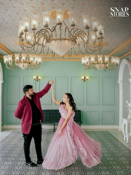 A playful dance under ornate chandeliers, capturing the couple's happiness in a grand, palace-like setting. This is a perfect example of a creative pre-wedding pose.