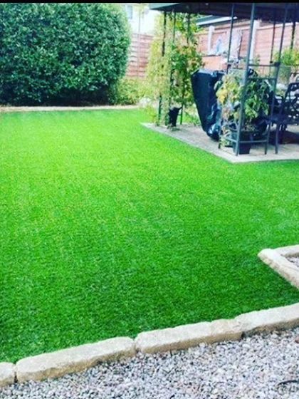 A rectangular backyard lawn made from artificial turf, edged with stone pavers. This is a practical, long lasting solution for a perfect looking lawn without the upkeep.