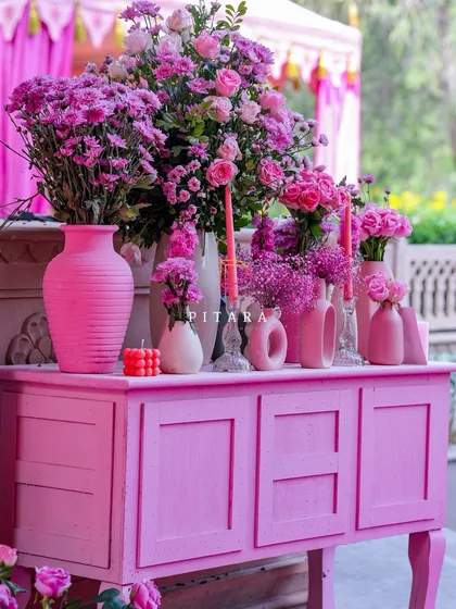 Another view of the pink console, this time showing the full piece of furniture painted to match the theme. The arrangement of vases and candles creates a beautiful vignette for a brunch or Mehendi.