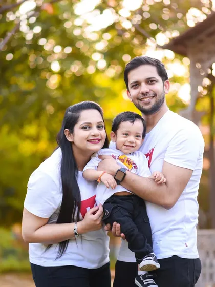 A classic family portrait with beautiful natural lighting in the background. Everyone is smiling, creating a timeless memory of Avyan's first birthday.