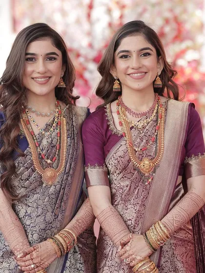 A portrait of the beautiful twin sisters. Both have soft, glowing makeup that enhances their features and complements their traditional sarees.