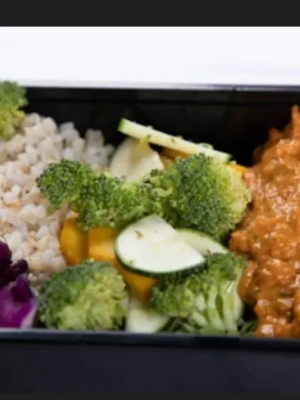 This meal box is packed with nutrients, featuring a protein-rich curry alongside brown rice and steamed vegetables like broccoli and zucchini. It's a well-rounded meal for any time of day.