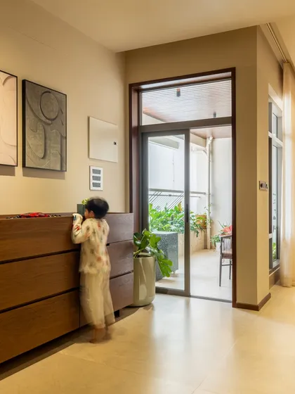A candid moment in the home, showing how the design facilitates everyday family life. The space allows for easy movement and connection, with views to the outdoor balcony.