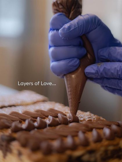 Layers of love. A glimpse of our pastry chef meticulously piping chocolate frosting, showing the care that goes into every single one of our creations.