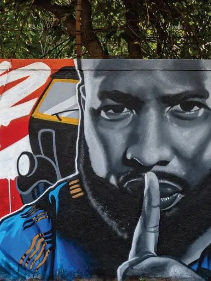 A close-up of the Kieron Pollard mural, highlighting the artist's skill in capturing a realistic portrait using only spray paint, complete with an auto-rickshaw detail in the background.