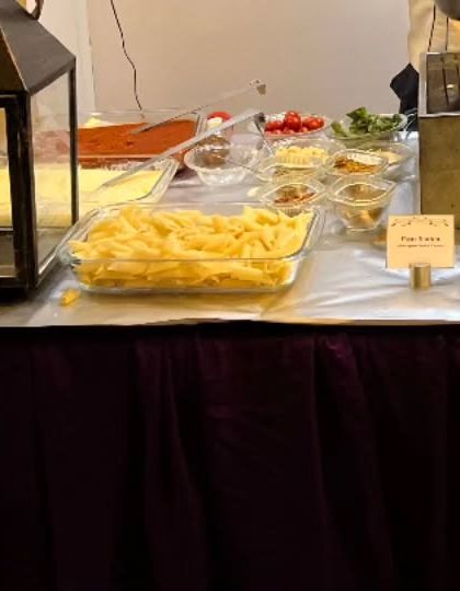 The ingredient setup for a live pasta station. Guests can choose their own pasta, sauce, and toppings for a personalized Italian meal made right in front of them.