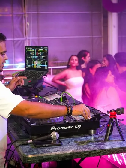 A side angle of me working the mixer at Gypsy Tower. You can see the crowd in the background, fully immersed in the purple-hued party atmosphere.