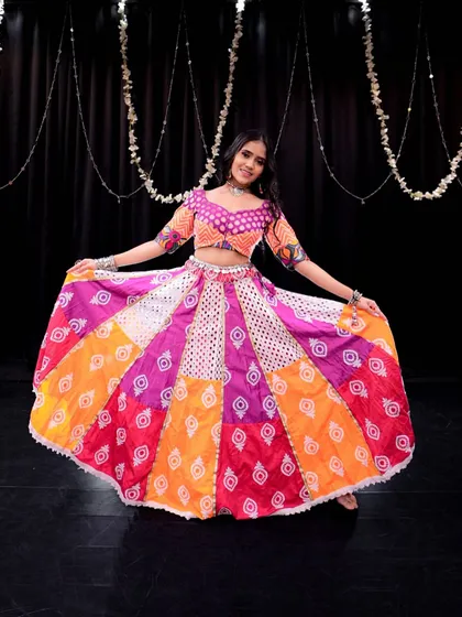 A beautiful photo showcasing a vibrant, multi-colored lehenga perfect for a Garba or Sangeet performance. This is the kind of look that makes a dance pop!