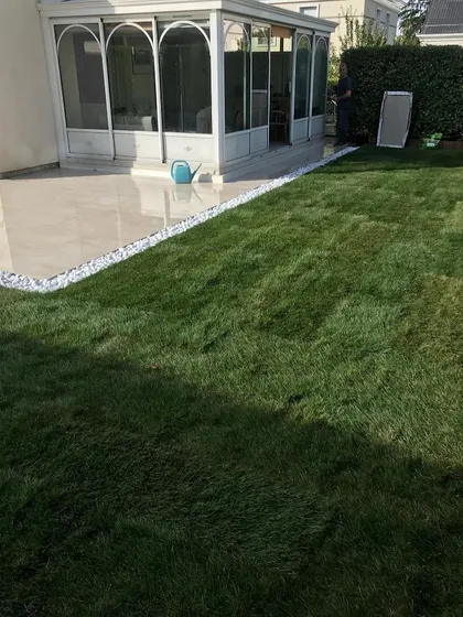 A freshly installed lawn next to a new patio, with a neat border of white pebbles. This shows the transition from construction to a finished garden.