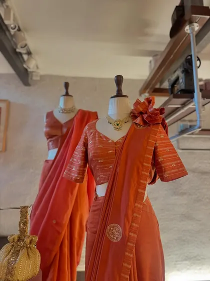 The beauty of a rust-orange saree. This piece is styled with a striped blouse and a dramatic floral shoulder accessory, showing how to personalize a traditional look.